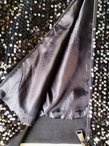 Detailed view of men's black sequin bomber jacket featuring inner lining and zipper