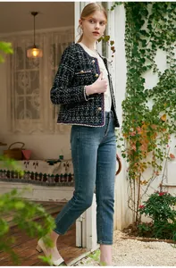 Model wearing an elegant black and white plaid tweed jacket styled with casual denim jeans.