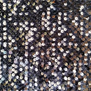 Close-up of shiny silver sequins on black fabric for a performance jacket detail