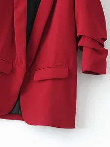 Detailansicht eines lebhaften roten Blazers mit Schalkragen, Taschen- und Texturdetails