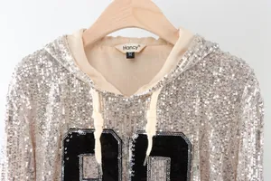 Close-up of sparkling silver sequined hoodie featuring bold black number embroidery detail