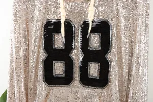Detailed view of the sparkling rose gold sequin hoodie featuring a black '88' patch
