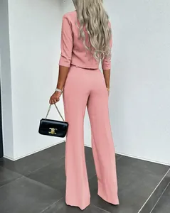 Vista trasera de un elegante conjunto de traje rosa de dos piezas con pantalón ancho.