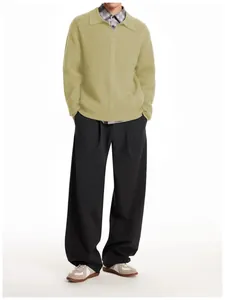 Full body view of man wearing a retro light yellow cable-knit polo sweater and black pants.