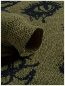 Nahaufnahme eines grünen Strickpullover-Bündchens mit Rippdetails und Augenmuster-Textur.