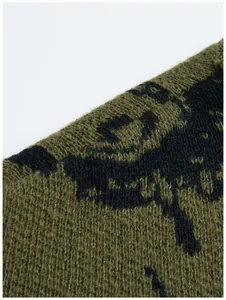 Detailaufnahme des gestrickten olivgrünen Augenmusters auf einer Streetstyle-Pullovertextur
