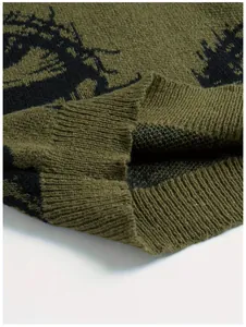 Nahaufnahme eines olivgrünen Strickpullovers mit schwarzem Augenmuster und Rippbündchen