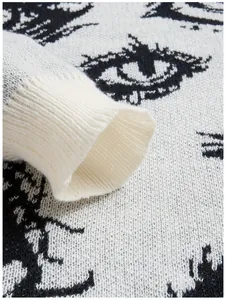 Detaillierte Nahaufnahme von Strickbündchen und dunklem Augenmuster auf weißem Pullover