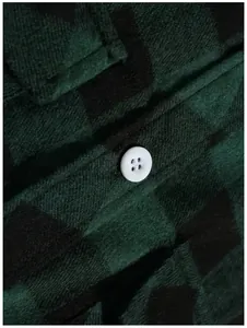 Macro-detail van de zachte textuur van een groen en zwart geruit overhemd met witte knoop.
