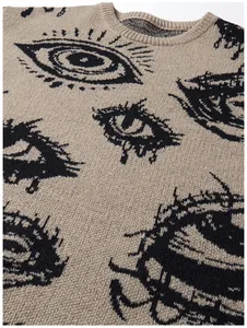 Detailaufnahme eines Strickpullovers mit dunklem Augenmuster und geripptem Rundhalsausschnitt.