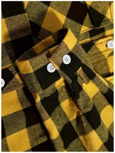 Detailopname van de mouwmanchet van een geel met zwart geruit heren flanellen overhemd.