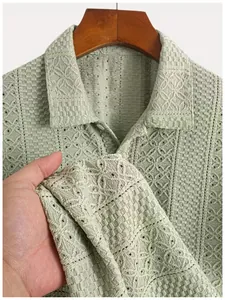 Close-up detail of green textured knit polo shirt showing intricate hollow-out patterns