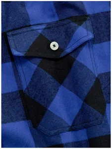 Detailopname van een blauw en zwart geblokte overhemdzak met witte knoop