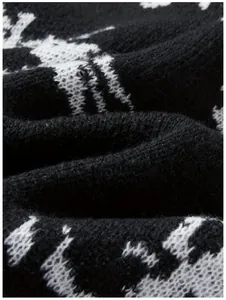 Nahaufnahme der weichen Stricktextur und des abstrakten Augen-Jacquards auf dem Pullover.