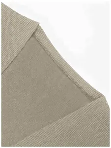 Gros plan sur les coutures fines et la texture du tissu d'un cardigan en maille taupe