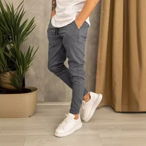 Moderni pantaloni jogger grigi da uomo in tessuto per abiti con scarpe da ginnastica bianche.