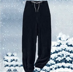 Close-up detail of black fuzzy fleece lounge pants with white drawstring in a snow scene