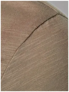 Detailed macro view of slub knit fabric texture and shoulder seam on men's Henley shirt