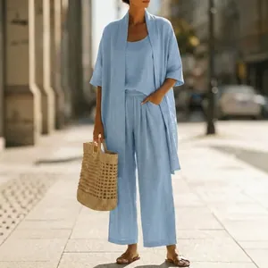 Full view of light blue three-piece linen resort set for women on a sunny street