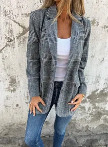 Close-up of a women's vintage grey plaid blazer worn over a white tank top and blue jeans.