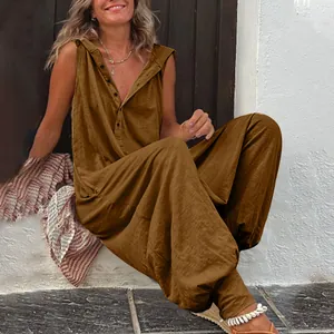 Γυναίκα κάθεται έξω φορώντας καφέ αμάνικη ολόσωμη φόρμα με κουκούλα και κουμπιά.