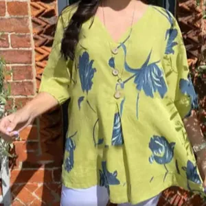 Detailed view of the vibrant green v-neck cotton linen blouse with large blue floral prints