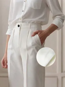Dettaglio che mostra la consistenza del tessuto liscio di questi pantaloni bianchi a vita alta