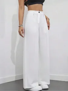 Dettaglio dei pantaloni bianchi a vita alta con gamba larga dal drappeggio elegante e stile minimal