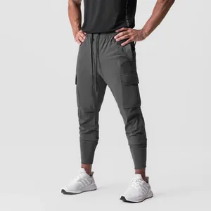 Detail view of men's dark grey cargo joggers with side pockets and elastic cuffs.