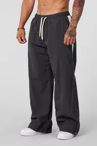 Close-up of men's wide-leg drawstring pants in charcoal grey with white side stripe
