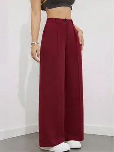 Dettaglio di pantaloni bordeaux a vita alta a gamba larga con tessuto drappeggiato.
