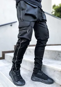 Close-up detail of black techwear cargo pants with multi-pockets and reflective piping