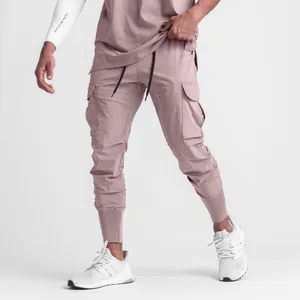 Men's pink fitness cargo joggers with multiple pockets and elastic cuffs detail.