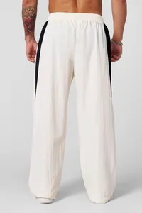 Rear view detail of men's loose off-white casual pants with black side stripes