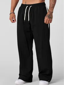 Men's loose black casual pants featuring white drawstring and side stripe accents