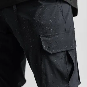 Detailed view of black water-resistant cargo pants fabric showing functional water droplets