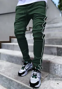 Close-up of dark green joggers with white side reflective piping and zipper pocket detail