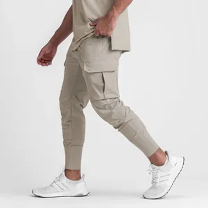 Detail view of men's khaki cargo joggers featuring a side flap pocket and tapered cuff
