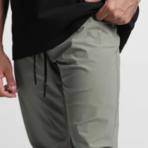 Close-up detail of olive green men's ice silk gym pants with black waist drawstring.