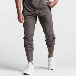 Detailed view of men's taupe fitness joggers with elasticated cuffs and drawstring.