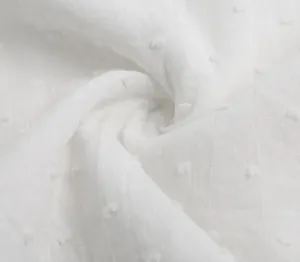 Macro detail of white pure cotton fabric with delicate Swiss dot texture and soft folds.