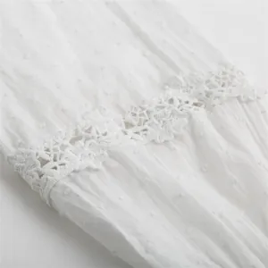 Detailed view of white swiss dot fabric and intricate floral lace trim on a blouse
