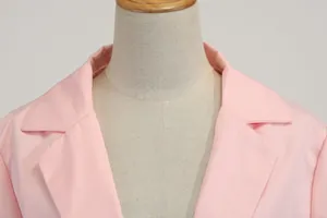 Macro detailopname van de reverskraag en textuur van een roze slim-fit damesblazer op een paspop