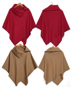Dettaglio di poncho con orlo asimmetrico rosso e cammello su grucce
