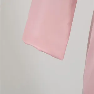 Gros plan du poignet d'un blazer rose montrant les coutures et la texture du tissu