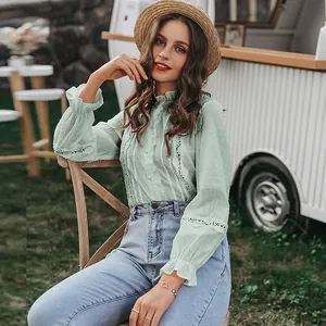Close-up of pastel green puff sleeve blouse with lace ruffles and dotted texture