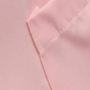 Gros plan sur la texture du tissu rose et les coutures d'une poche de veste pour femme.