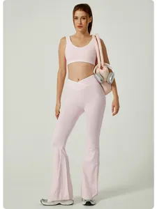 Full body shot of a model wearing a pink crossover waist yoga set with flared pants.