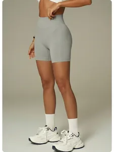 Detail view of grey high-waisted seamless yoga shorts worn by model with white sneakers