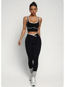 Vista completa di una modella in reggiseno sportivo nero e legging yoga con bordo bianco.